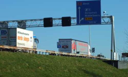 Foto van snelweg met bord afslag Oirschot en twee vrachtwagens