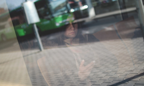 Foto van vrouw in bushokje met telefoon