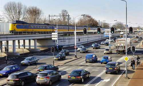 Straatbeeld met trein en auto's bij een viaduct in Eindhoven