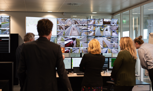 Foto van verkeerscentrale, mensen kijken naar grote schermen met verkeer