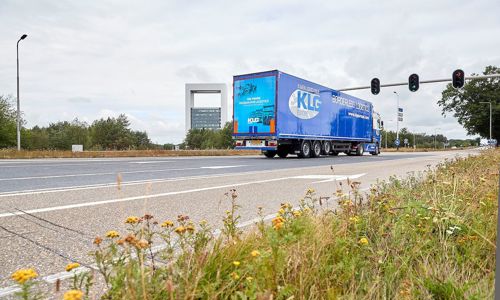 Foto van een blauwe vrachtwagen die richting een stoplicht rijdt